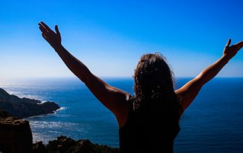 a woman standing on top of a mountain with her arms outstretched